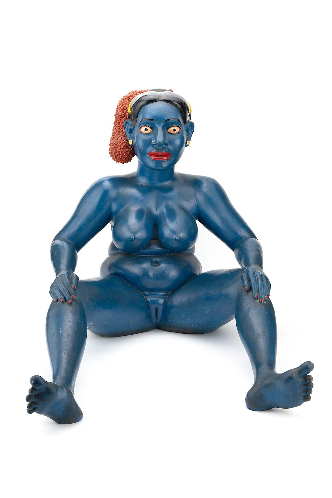 This is a sculpture of a blue-skinned, nude woman with wide eyes and a rounded body. 