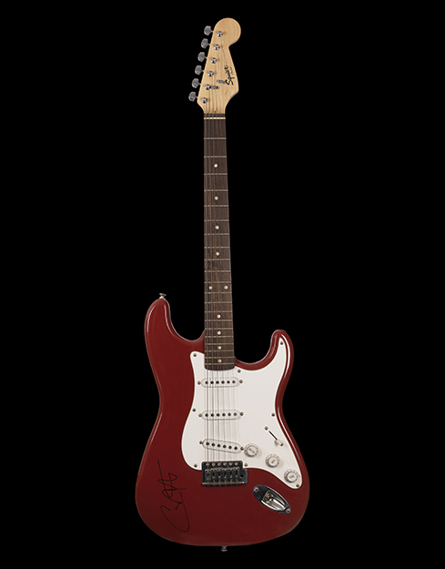 A dark red guitar with a white design shaping the body.