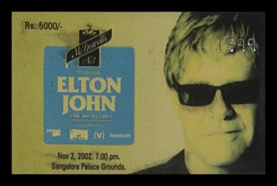 Elton John’s face appears next to a blue box with his name on it. The text reads Rs 5000 at the corner of the ticket.
